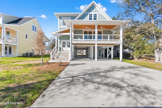 raised beach house with a porch, ceiling fan, a front lawn, and a carport