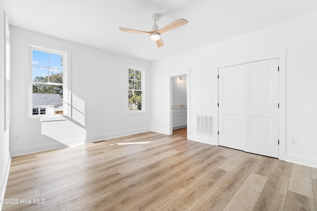 unfurnished bedroom featuring light hardwood / wood-style floors, ceiling fan, ensuite bathroom, and multiple windows