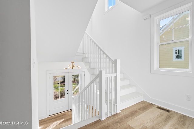 staircase featuring hardwood / wood-style flooring, an inviting chandelier, and plenty of natural light