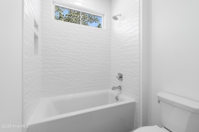 bathroom with tiled shower / bath combo and toilet