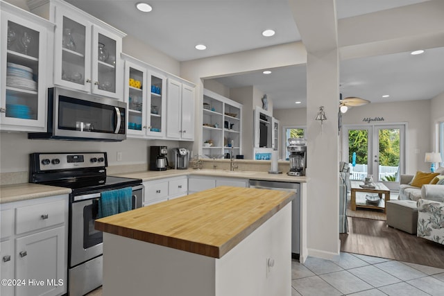 kitchen featuring a kitchen island, white cabinetry, appliances with stainless steel finishes, light wood-type flooring, and ceiling fan