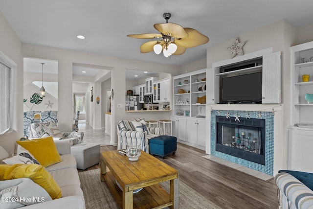 living room featuring ceiling fan, a tile fireplace, and dark hardwood / wood-style floors