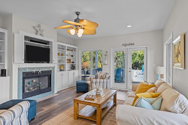 living room with ceiling fan, a tile fireplace, and dark hardwood / wood-style floors