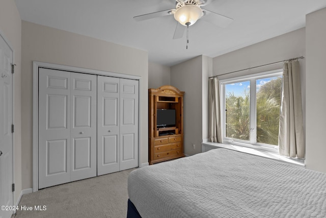 bedroom with light colored carpet, ceiling fan, and a closet