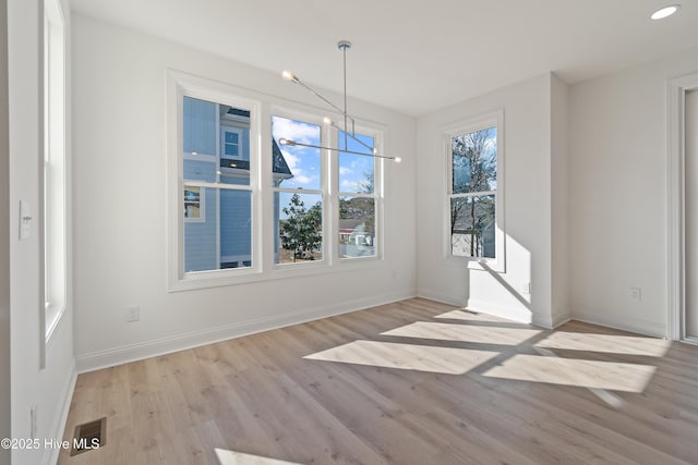 unfurnished dining area featuring light hardwood / wood-style floors and a notable chandelier