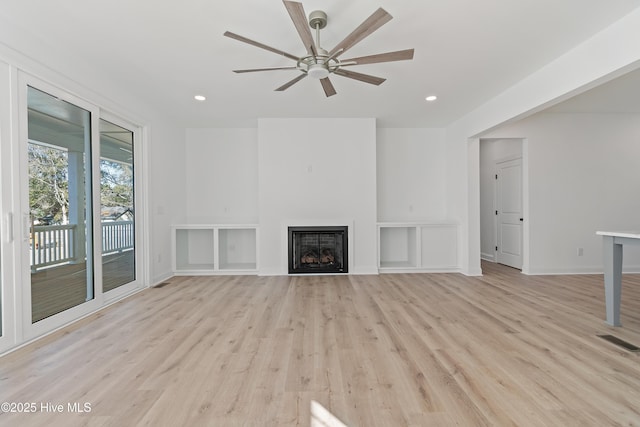 unfurnished living room featuring ceiling fan, light hardwood / wood-style flooring, and built in shelves