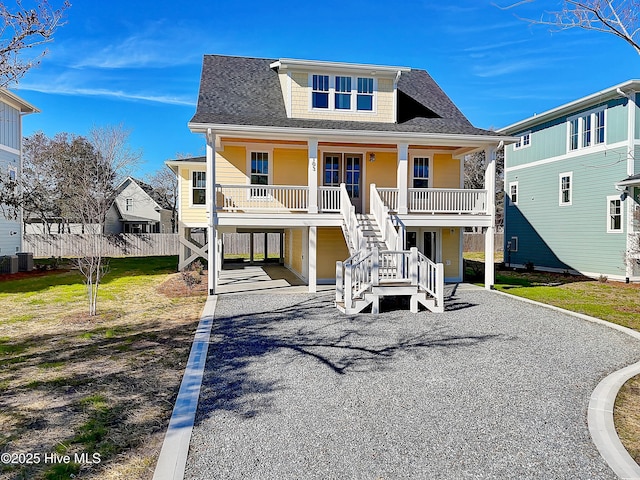 raised beach house featuring covered porch, cooling unit, a carport, and a front yard