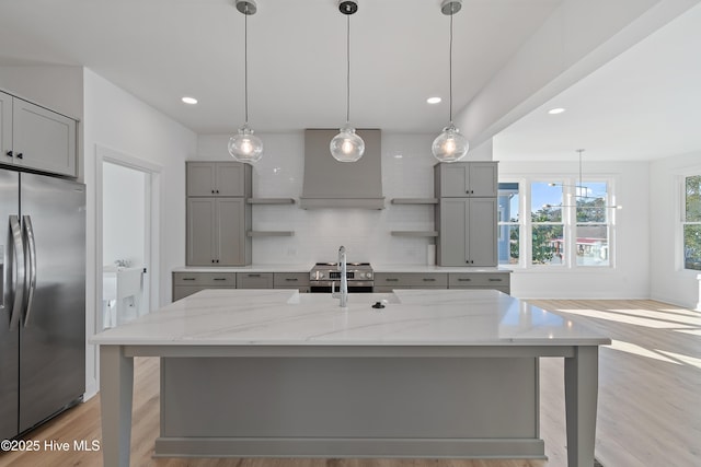 kitchen with hanging light fixtures, stainless steel appliances, light stone counters, and a spacious island