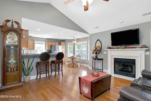 living room featuring ceiling fan, lofted ceiling, and light wood-type flooring