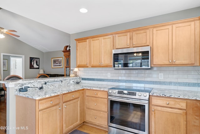 kitchen featuring kitchen peninsula, stainless steel appliances, vaulted ceiling, decorative backsplash, and light hardwood / wood-style flooring