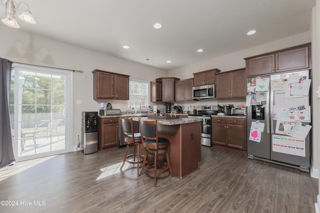 kitchen featuring dark hardwood / wood-style flooring, stainless steel appliances, a kitchen island, and plenty of natural light