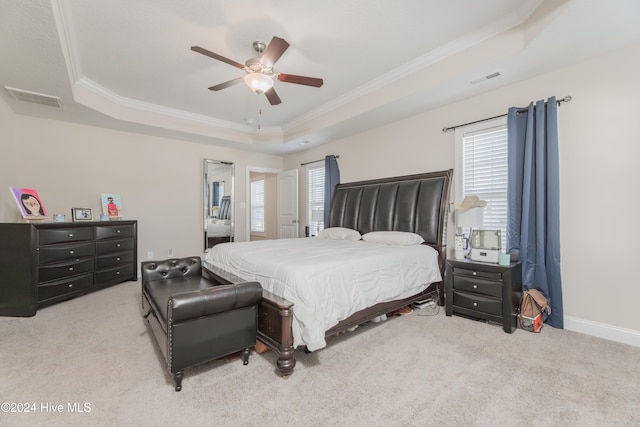 carpeted bedroom with ceiling fan, multiple windows, a raised ceiling, and ornamental molding