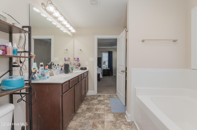 bathroom featuring a washtub, vanity, and toilet