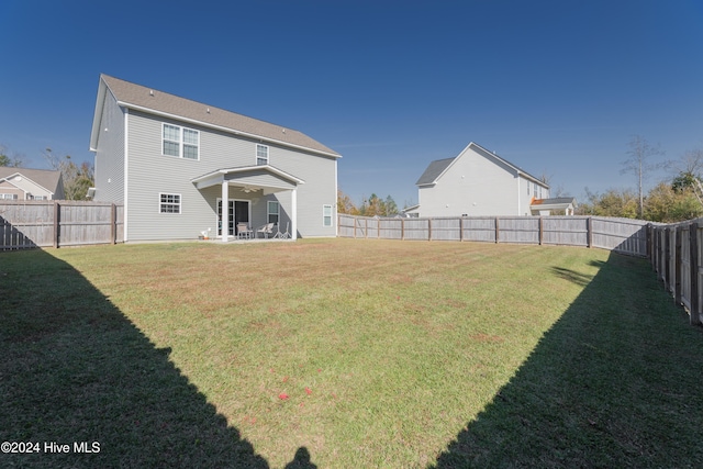 rear view of property featuring a lawn and a patio