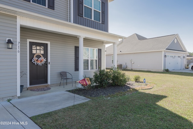 view of exterior entry featuring central AC unit, a garage, a lawn, and covered porch