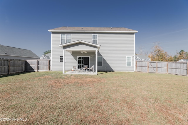 rear view of house featuring ceiling fan, a yard, and a patio area