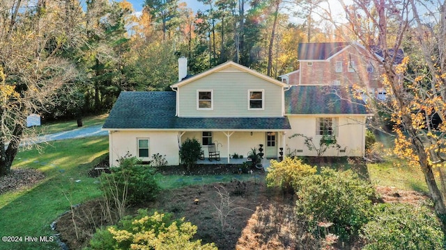 rear view of property featuring a porch and a lawn