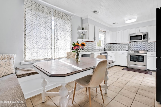 kitchen with white cabinets, decorative backsplash, ornamental molding, and appliances with stainless steel finishes