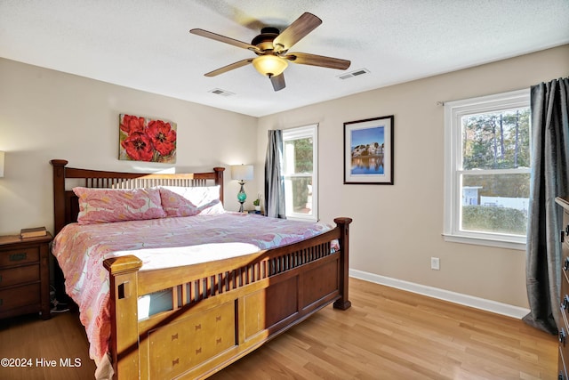 bedroom featuring ceiling fan, light hardwood / wood-style floors, and a textured ceiling