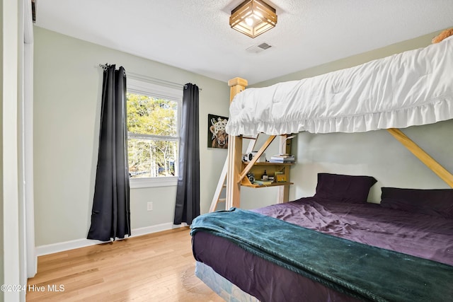 bedroom with hardwood / wood-style floors and a textured ceiling