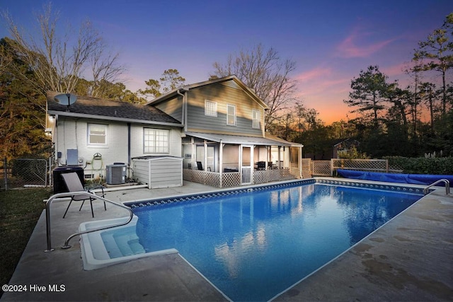 pool at dusk with central AC and a sunroom