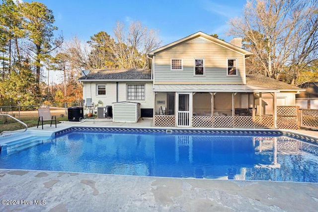 rear view of house with central air condition unit and a sunroom