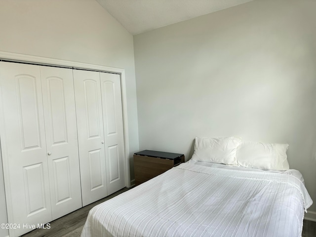 bedroom with vaulted ceiling, a closet, and dark hardwood / wood-style floors