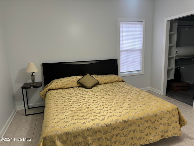 bedroom with a walk in closet and light tile patterned floors