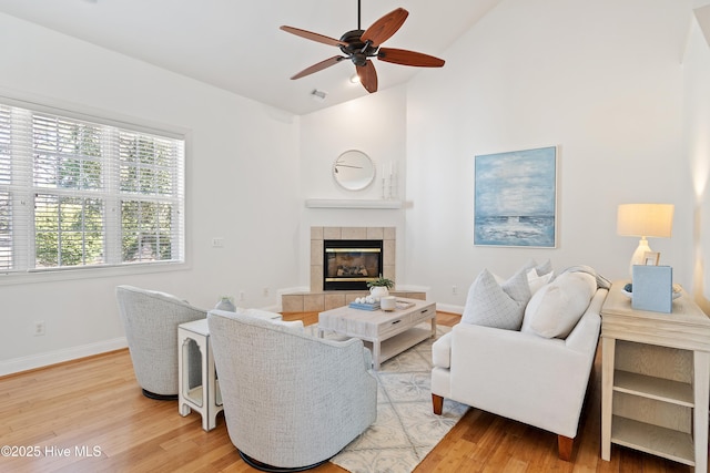 living area with lofted ceiling, light wood-type flooring, baseboards, and a tile fireplace