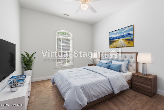 bedroom featuring a ceiling fan, wood finished floors, visible vents, and baseboards