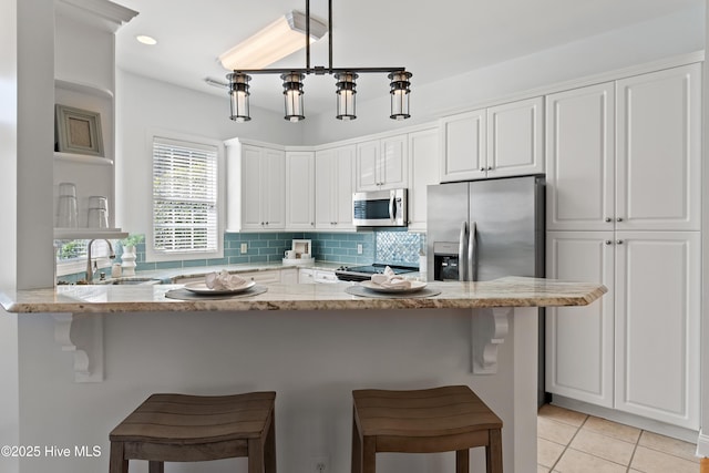 kitchen with appliances with stainless steel finishes, backsplash, a sink, and light stone counters