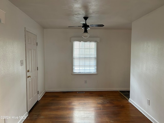 empty room with dark wood-type flooring and ceiling fan