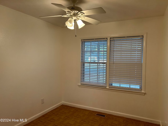 empty room featuring dark parquet flooring and ceiling fan