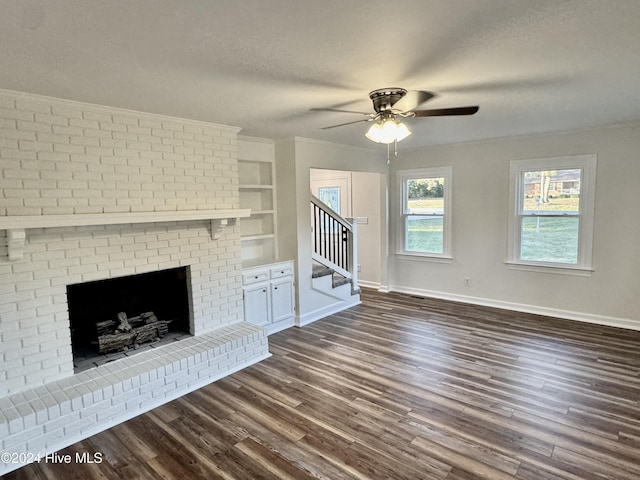 unfurnished living room featuring dark wood-type flooring, ceiling fan, built in features, a fireplace, and a textured ceiling