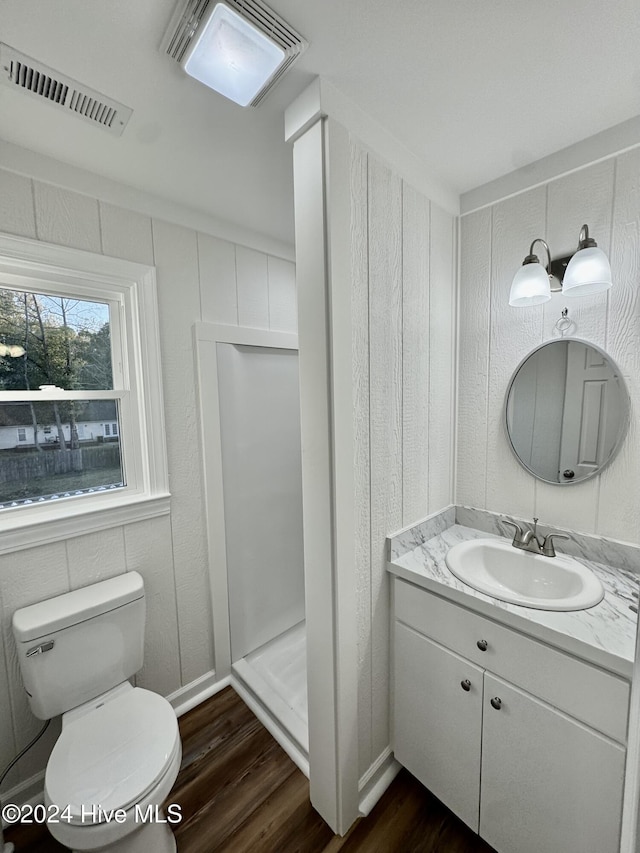 bathroom with hardwood / wood-style flooring, vanity, toilet, and walk in shower