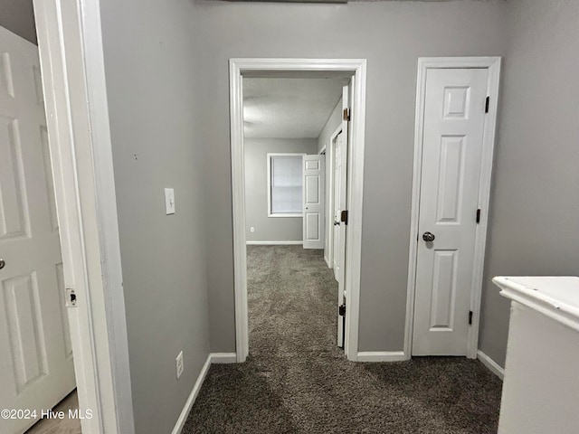 corridor with a textured ceiling and dark carpet