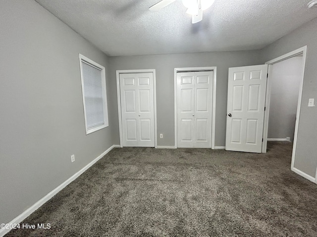 unfurnished bedroom with multiple closets, dark colored carpet, a textured ceiling, and ceiling fan