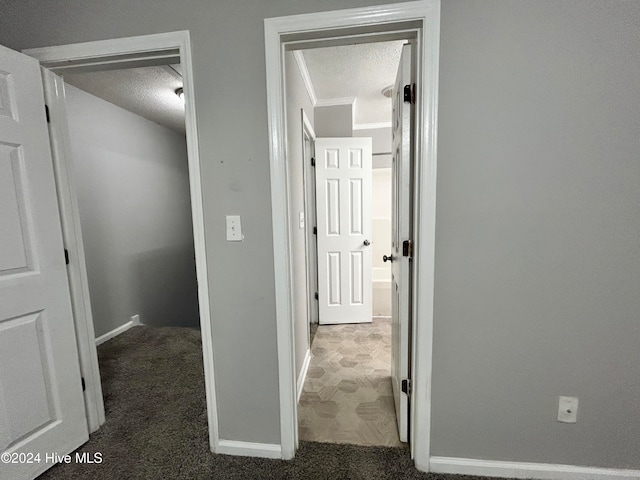 hallway featuring ornamental molding, a textured ceiling, and dark carpet