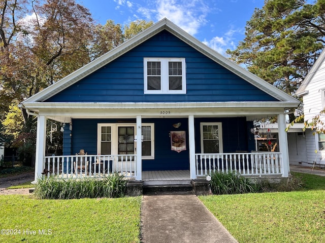 bungalow with covered porch and a front yard