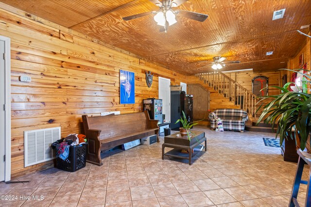 living room with ceiling fan, wooden ceiling, light tile patterned floors, and wooden walls