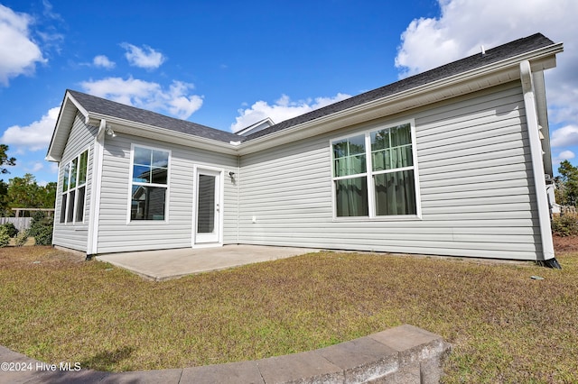 rear view of house with a patio and a lawn