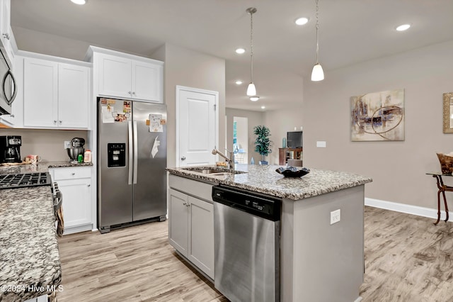 kitchen with appliances with stainless steel finishes, light wood-type flooring, a center island with sink, and white cabinets