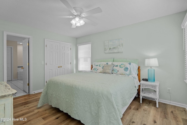 bedroom with a closet, light hardwood / wood-style floors, and ceiling fan