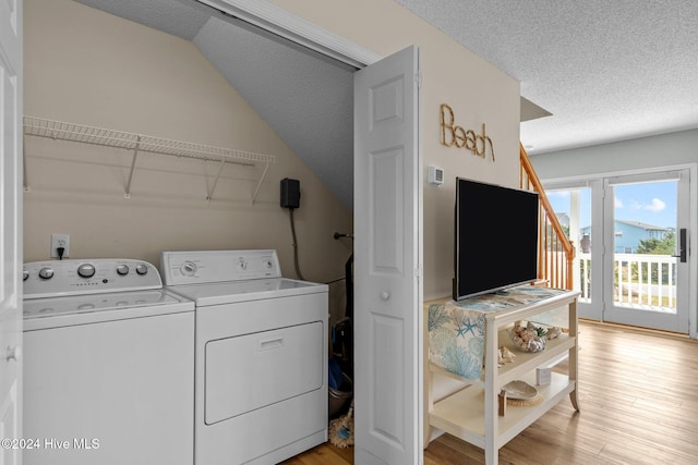 laundry room with washer and dryer, a textured ceiling, and light hardwood / wood-style floors