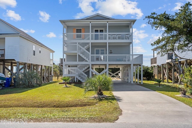 raised beach house with a front lawn and a carport