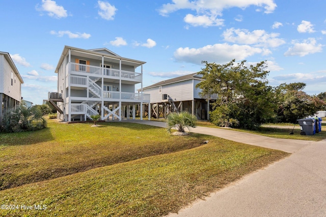 coastal home featuring a balcony, a front lawn, and a carport