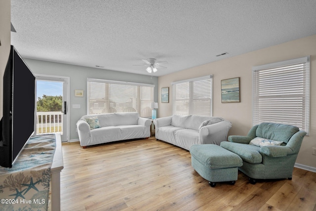 living room featuring light hardwood / wood-style floors, a textured ceiling, and ceiling fan