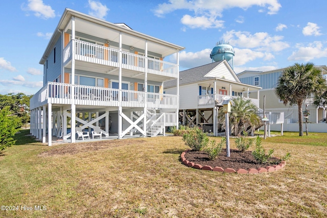 rear view of house featuring a balcony and a lawn