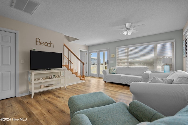 living room with french doors, light hardwood / wood-style flooring, a textured ceiling, and ceiling fan