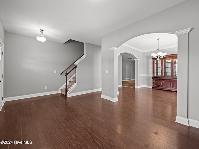 unfurnished living room featuring a chandelier, ornamental molding, arched walkways, and wood finished floors